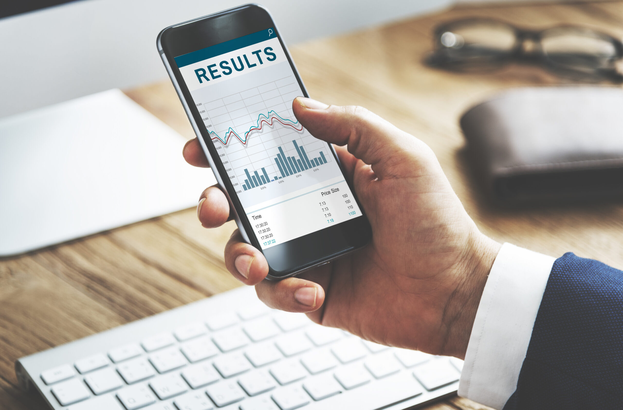 Hand holding a smartphone showing marketing results and performance metrics.